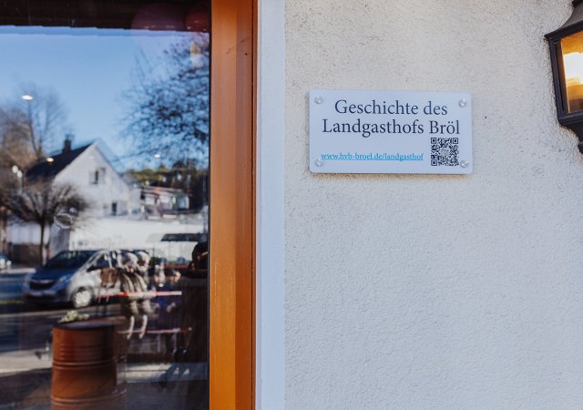 Eine Tafel mit QR-Code ist an der Außenfassade angebracht und informiert über die Geschichte des Gebäudes. Fotonachweis: Julia Holland/REGIONALE 2025 Agentur